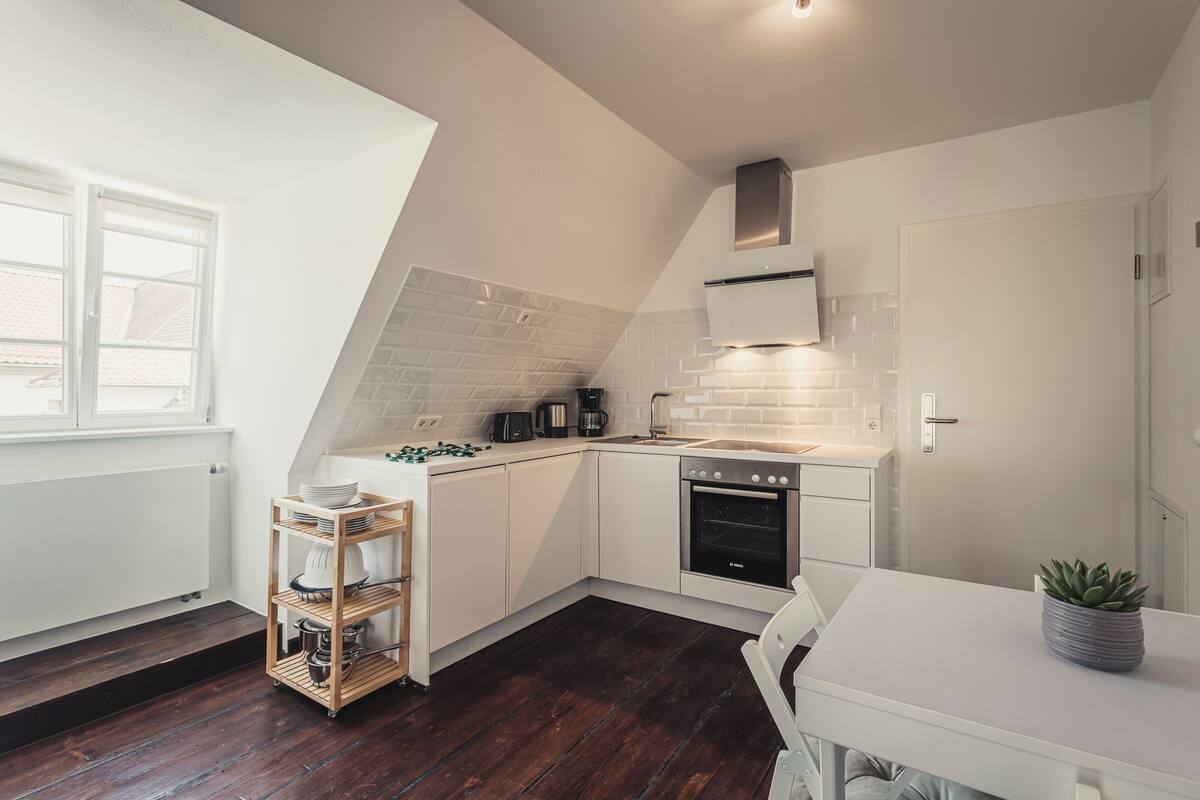 A modern kitchen with white cabinets, a black oven, and a white countertop.