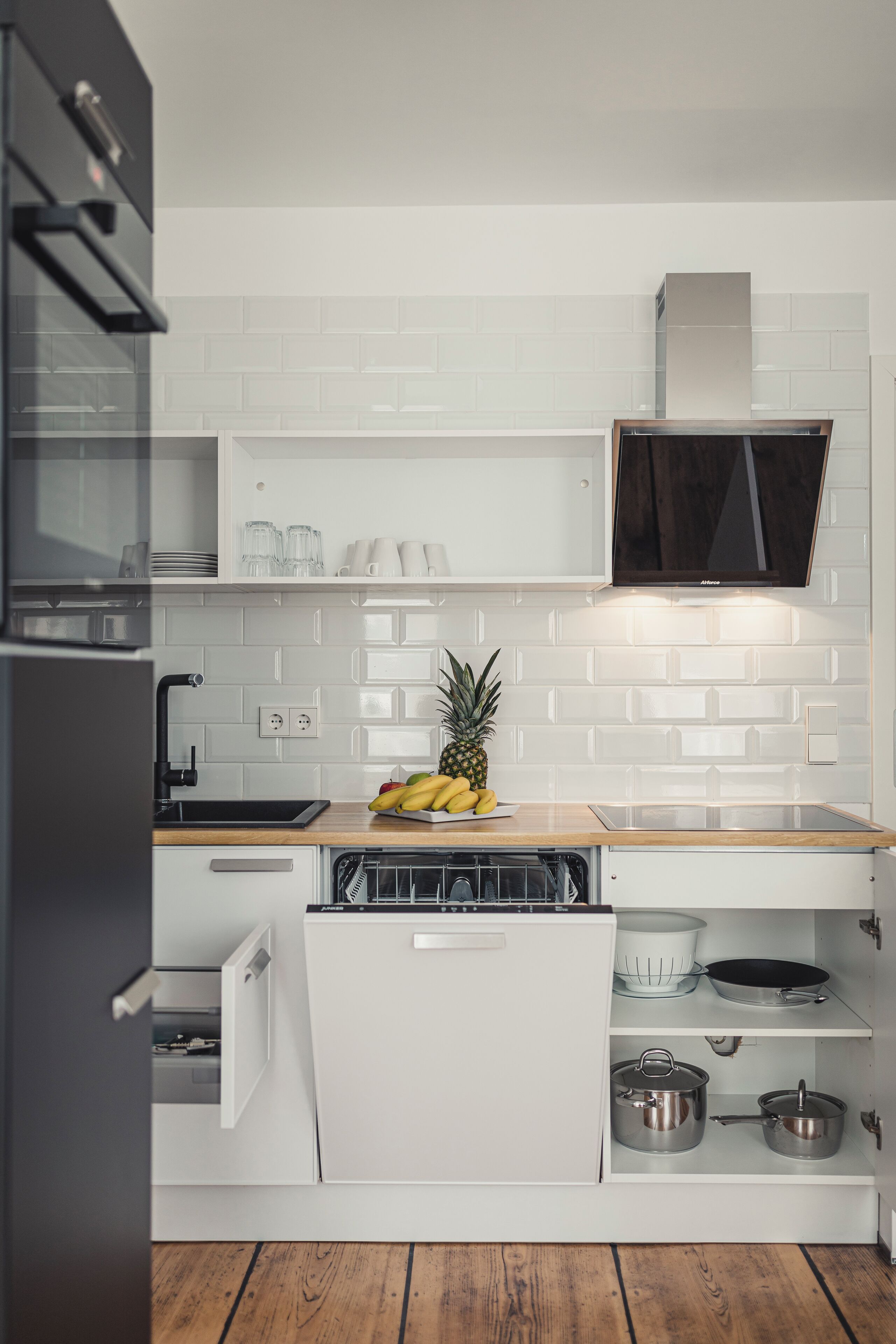 A compact kitchen with white cabinetry, a wooden countertop, and a built-in oven.
