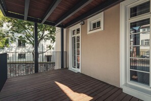 A wooden deck with a pergola, a white building with a window, and a view of another building in the background. - Heimbach Apartments Lahr (Lahr)