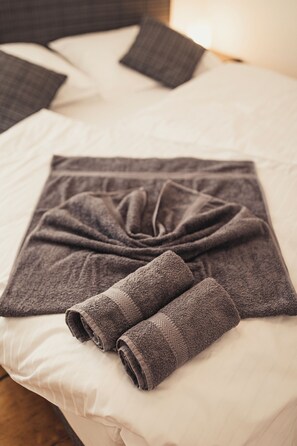A neatly made bed with a folded blanket and two rolled towels. - Heimbach Apartments Lahr (Lahr)
