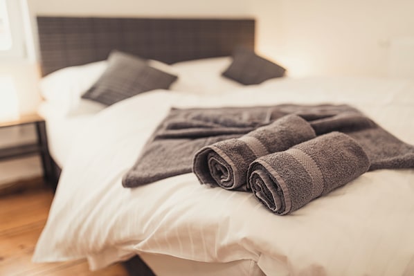A neatly made bed with rolled towels and pillows. - Heimbach Apartments Lahr (Lahr)