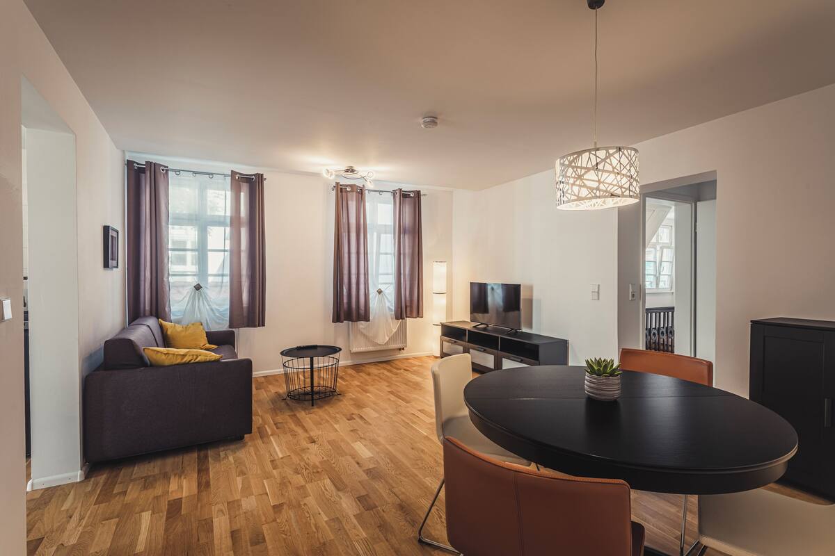 A modern living room with a sofa, a dining table, and a TV.