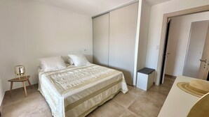 Ein Schlafzimmer mit Bett, Nachttisch, Kleiderschrank und kleinem Schreibtisch.