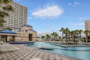 Relax by the pool surrounded by palm trees and lounge chairs.