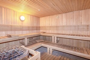 Relax in a serene sauna room with a sloped ceiling and comfortable seating for individual or group use.