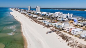 Eine Küstenlandschaft mit Strandhäusern, darunter mehrstöckige Gebäude und eingeschossige Häuser, einige mit Balkonen.