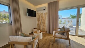 A modern living room with two wooden chairs, a flat-screen TV, and a large window with curtains. - Marinha Grande Apartamentos Rainbow N°9 (Marinha Grande)