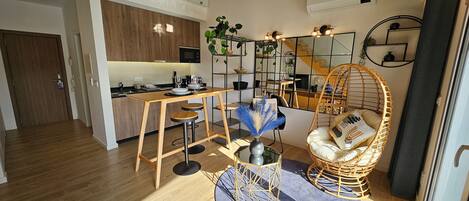 A modern apartment with a kitchen, dining area, and a living space with a hanging chair and a round table.