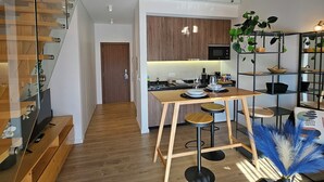A modern apartment with a loft bedroom, a kitchen with wooden cabinets, and a dining area with bar stools. - Marinha Grande Apartamentos Duo N°7 (Marinha Grande)