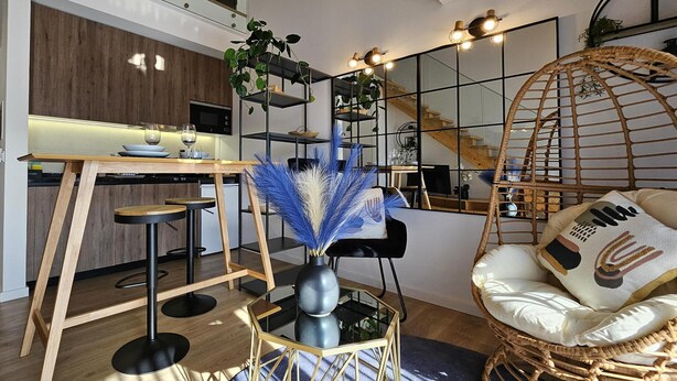 A modern kitchen with a wooden countertop, bar stools, and a decorative vase. - Marinha Grande Apartamentos Duo N°7 (Marinha Grande)