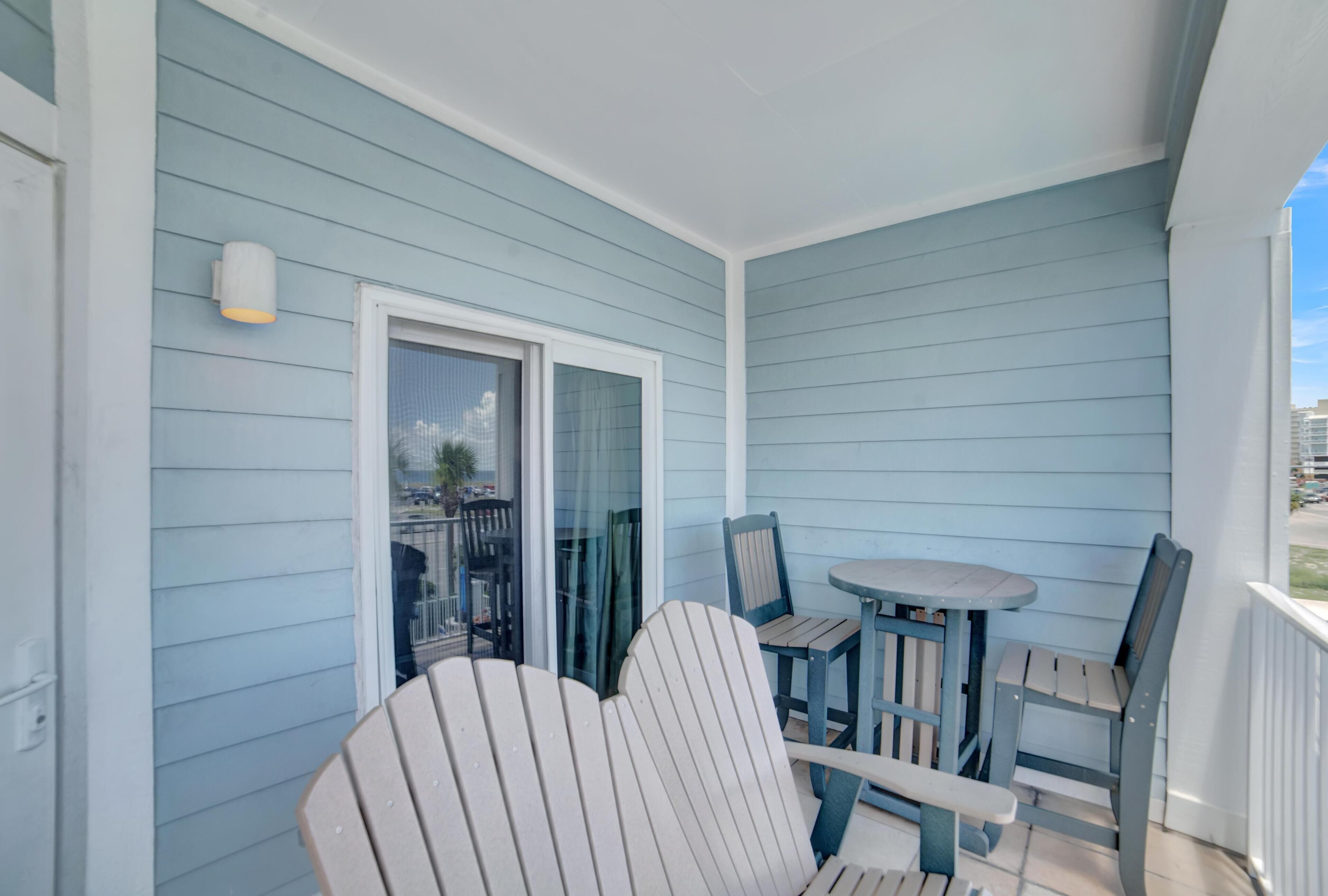Un balcon avec un revêtement bleu clair, une porte vitrée et une petite table avec des chaises.