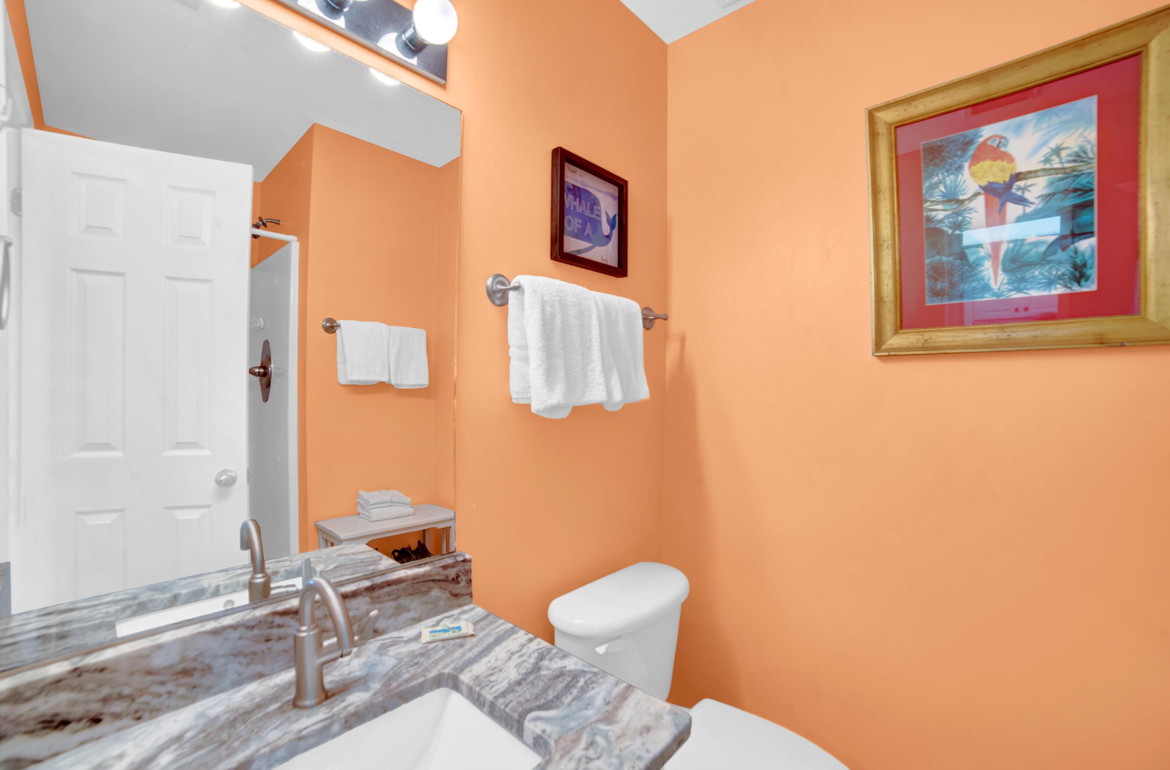 A bathroom with a marble sink, white toilet, and a framed painting on the wall.