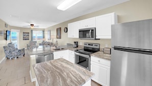 A modern kitchen with white cabinets, stainless steel appliances, and a marble countertop. - Grand Caribbean 209 (Orange Beach)
