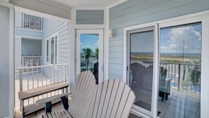 A balcony with a view of the beach, a chair, and a bench. - Grand Caribbean 209 (Orange Beach)