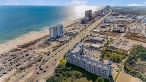 An aerial view of a coastal city with a beachfront hotel, roads, and surrounding buildings. - Grand Caribbean 209 (Orange Beach)