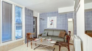 A living room with a sofa, two chairs, a coffee table, and a dining table set for two. - Paris Maison Lombards Terrasse (Paris)