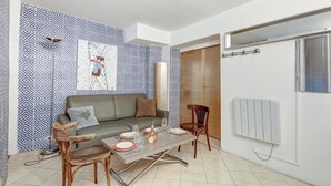 A modern living room with a patterned wall, a sofa, a dining table with chairs, and a radiator. - Paris Maison Lombards Terrasse (Paris)