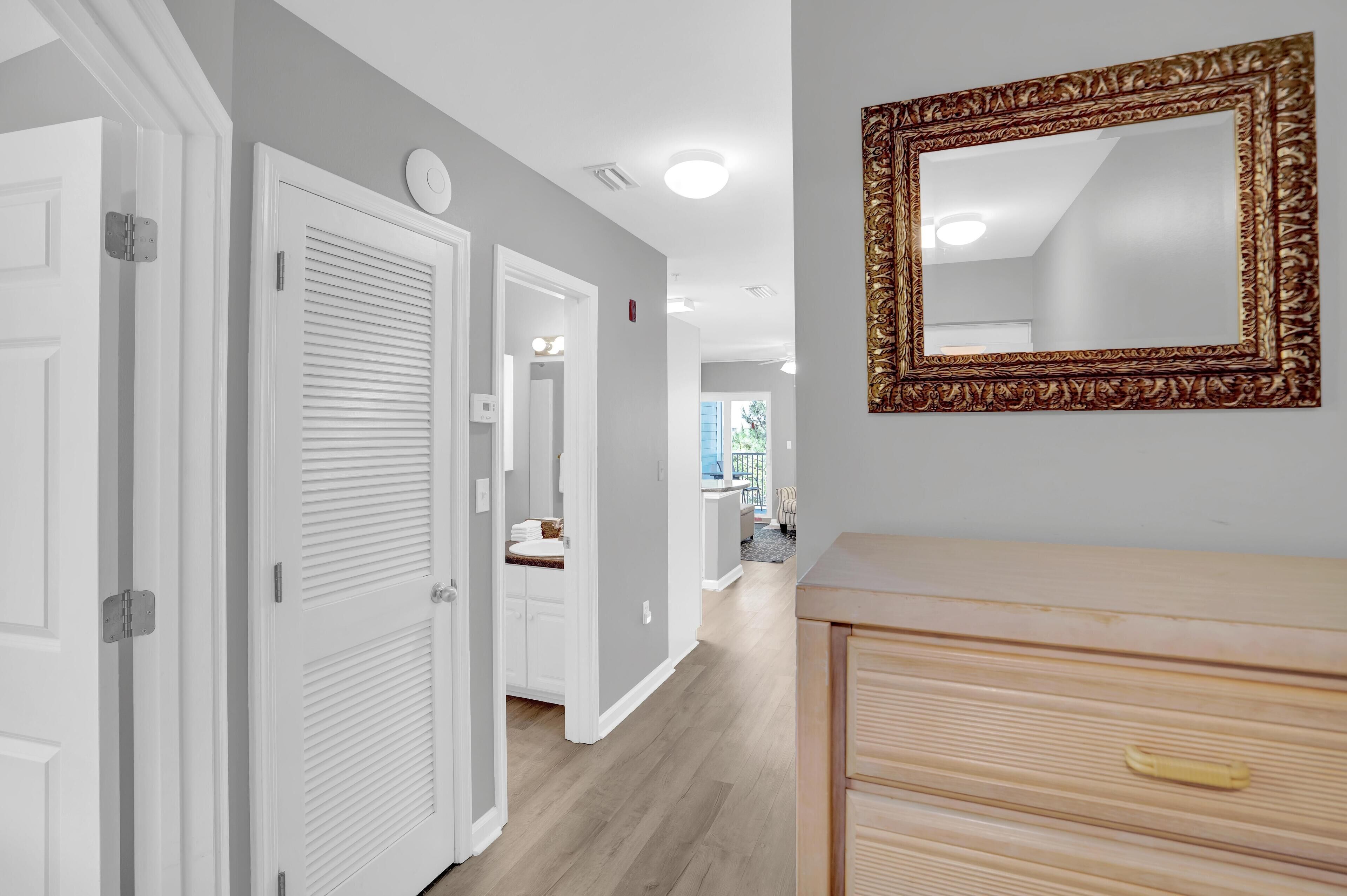 A hallway with white doors, a wooden dresser, and a large ornate mirror on the wall.