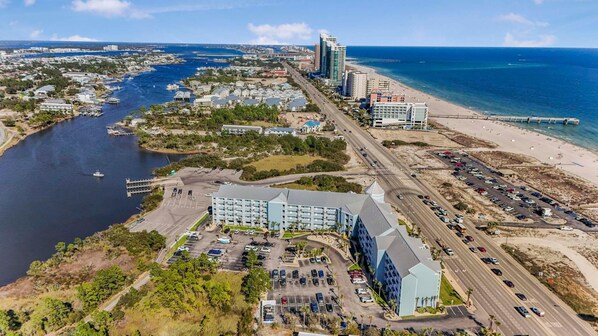 A coastal cityscape with a marina, a large hotel with multiple floors, and a beach area. - Grand Caribbean 225 (Orange Beach)