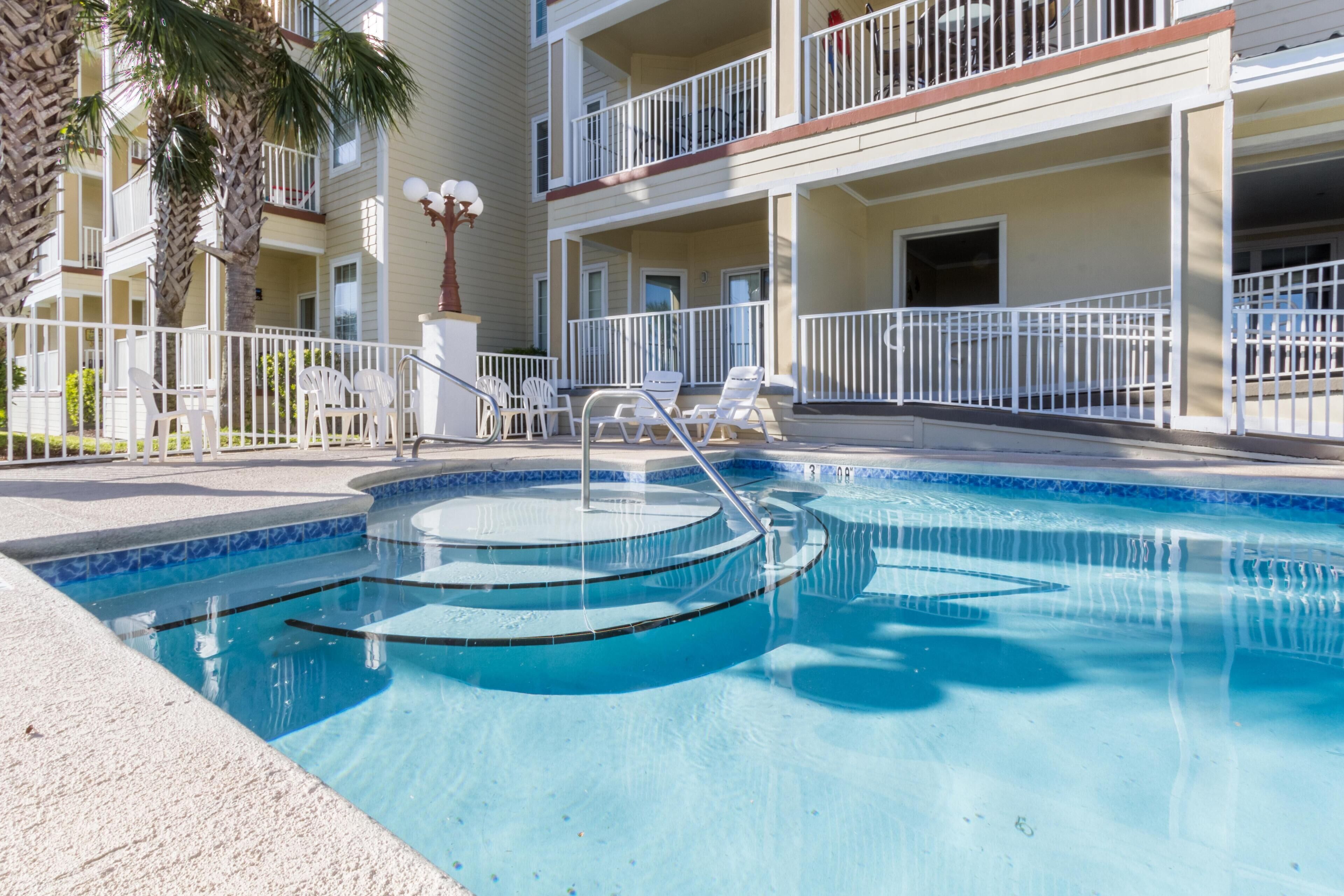 A swimming pool with steps, white lounge chairs, and a palm tree.