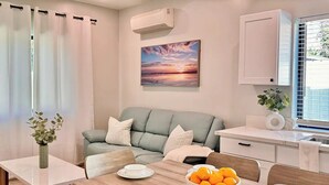 Una sala moderna con sofá, mesa de comedor y zona de cocina.