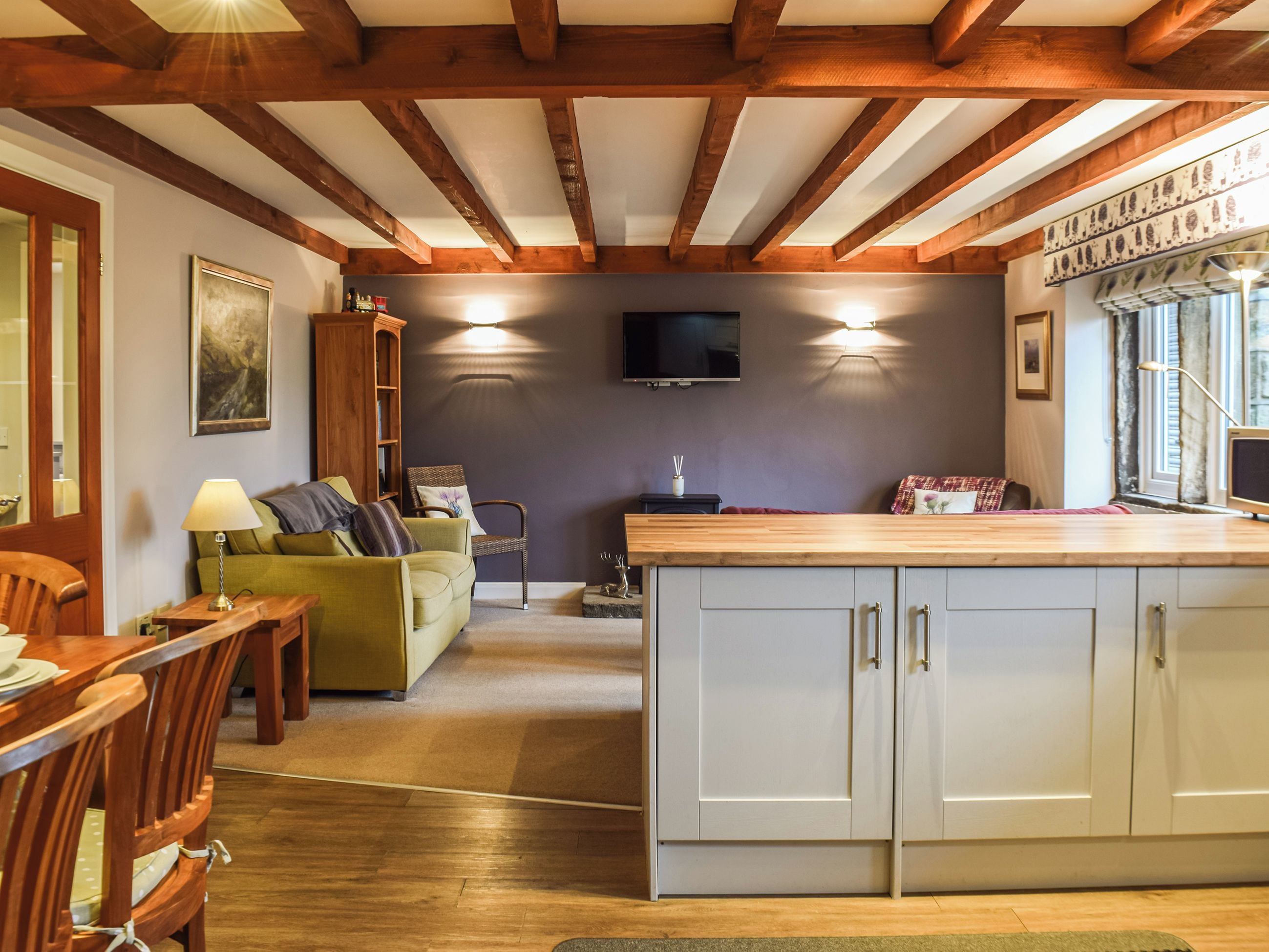 A cozy interior with a dining area, a sofa, a television, and a kitchen counter.