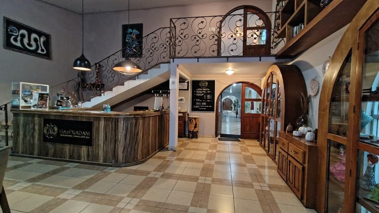 A hotel lobby with a reception desk, a staircase, and a check-in counter.