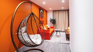 En moderne stue med en hængestol, en rød sofa og et lille sofabord.