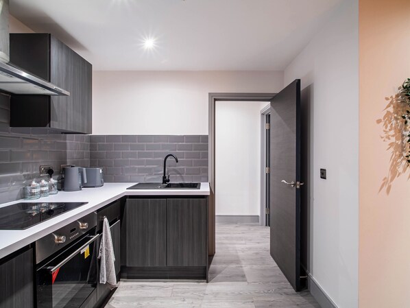 A modern kitchen with grey cabinetry, a black stove, and a sink. - Bradford Bliss Apartment (Bradford)