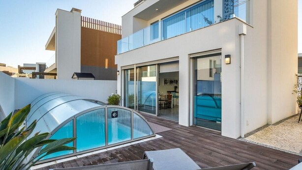 A modern house with a glass-enclosed pool, a wooden deck, and a dining area. - Silvercoast Villa Concha Baia - private heated pool and rooftop seaview lounge. (Salir do Porto)