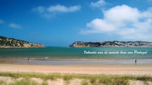 A beach with clear skies and calm waters, featuring a person walking and another standing in the distance. - Silvercoast Villa Concha Baia - private heated pool and rooftop seaview lounge. (Salir do Porto)