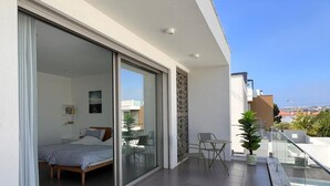 A modern balcony with a bed, a dining area, and a view of the city. - Silvercoast Villa Concha Baia - private heated pool and rooftop seaview lounge. (Salir do Porto)