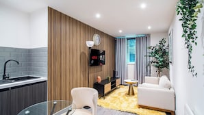 Una cocina moderna con un lavamanos integrado, una mesa de comedor de vidrio y una zona de estar acogedora con un sofá y una mesita redonda.