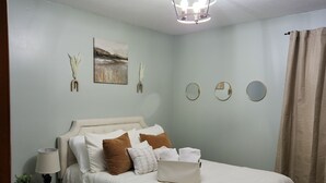 Une chambre à coucher bien rangée, avec un lit, une table de chevet, une lampe et des éléments décoratifs sur les murs.
