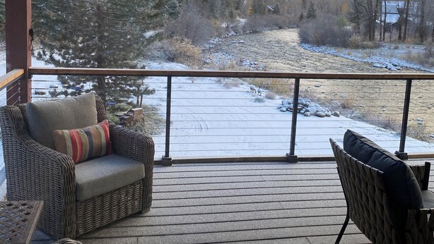 A covered outdoor deck with wicker furniture and a view of a snowy landscape.