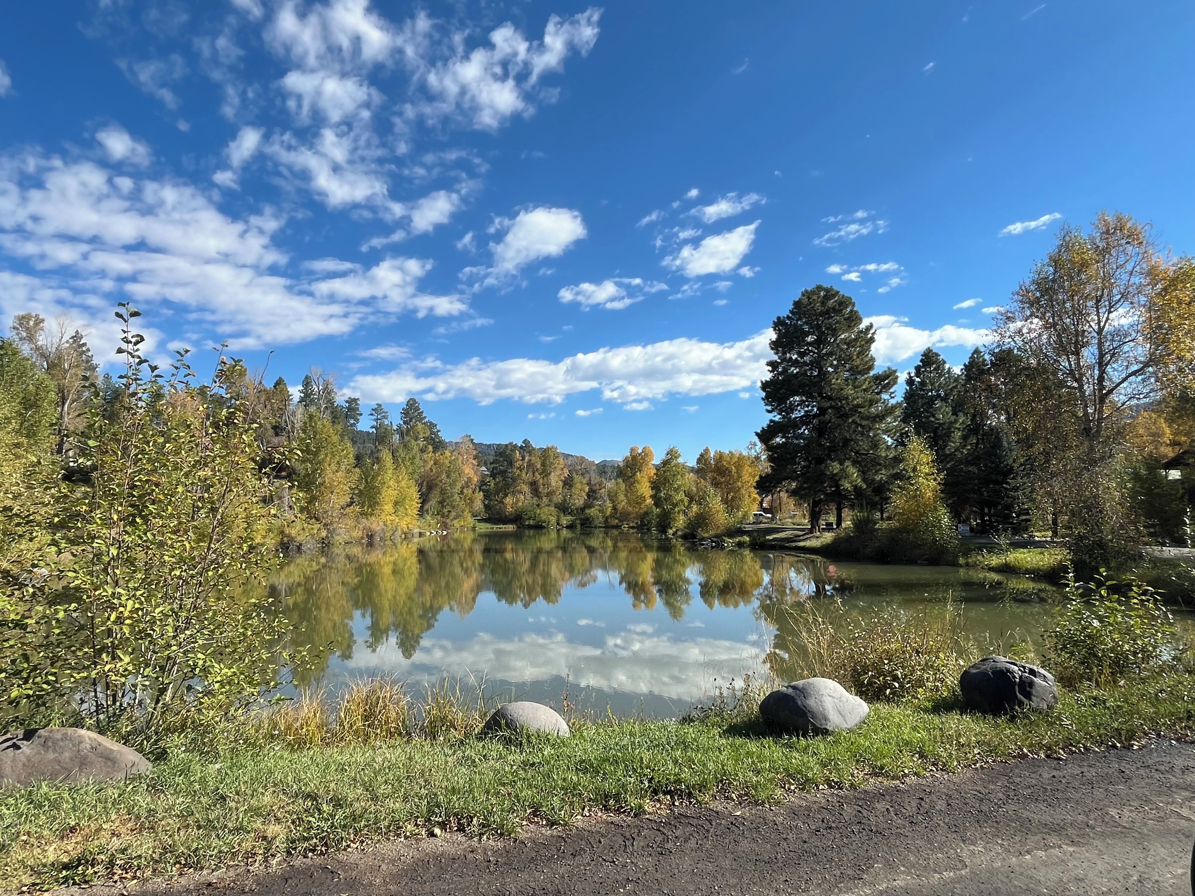 Un lago sereno con reflejos claros, rodeado de árboles y rocas.