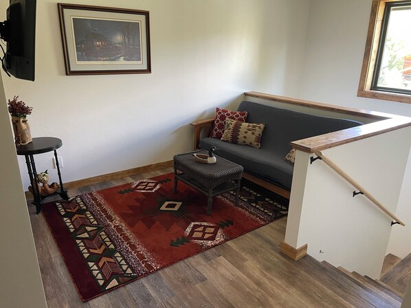 A living room with a sofa, a small table, a patterned rug, and a framed picture on the wall.