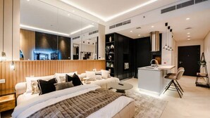 Una habitación de hotel moderna con una cama grande, una zona de estar, una kitchenette y un comedor.