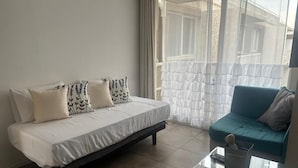 A modern bedroom with a bed, a sofa, and a glass coffee table. - Apartamento Familiar en Santiago (Santiago)