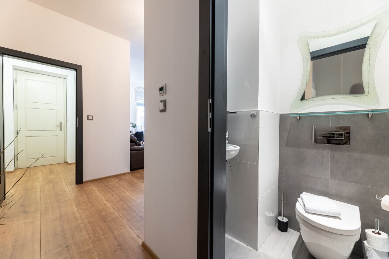 Ein modernes Badezimmer mit Duschkabine aus Glas, einer weißen Toilette und einem wandmontierten Waschbecken.