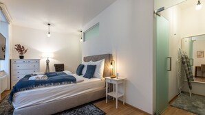 A bedroom with a bed, bedside table, lamp, and a mirror. - Peaceful & Cozy Living in Vyšehrad with a Balcony by EasyBNB Premium (Prague)