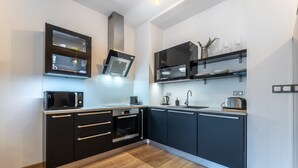 A modern kitchen with black cabinets, a microwave, a kettle, and a toaster. - Peaceful & Cozy Living in Vyšehrad with a Balcony by EasyBNB Premium (Prague)