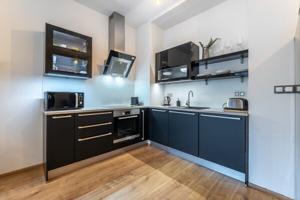 Enjoy cooking in this kitchen with a range hood, microwave, and oven, along with a stainless steel sink.