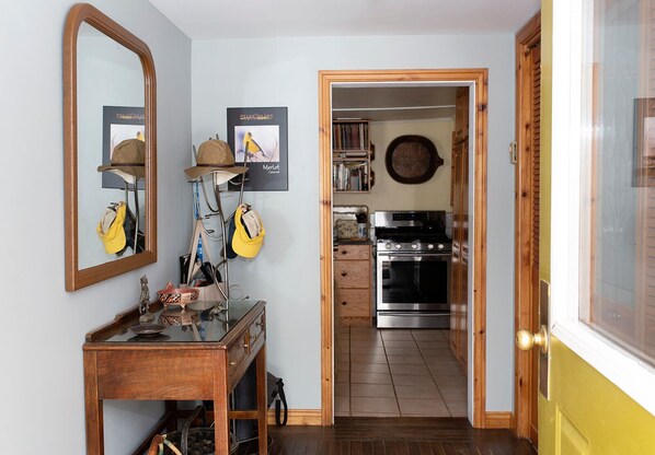 A narrow hallway leading to a kitchen with a stove and cabinets.