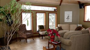 Un salón acogedor con un ventanal grande, un sofá, una silla y una planta en maceta.