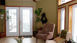 Una sala de estar con un piano, un sillón estampado, un sofá y una planta en maceta.