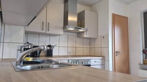 Een moderne keuken met een roestvrijstalen spoelbak, een inbouwoven en een afzuigkap.