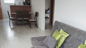 Una sala de estar con un sofá gris, dos cojines verdes y un tapete marrón.