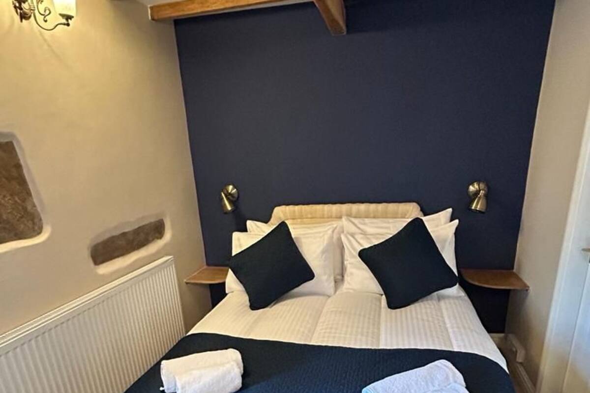 Une chambre à coucher avec un lit, des oreillers et une couverture bleue.