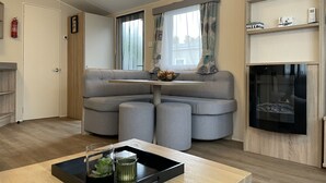A modern living room with a grey sectional sofa, a small table with a tray, a fireplace, and a window with curtains. - RBR 1132 - Beach Resort Kamperland (Kamperland)